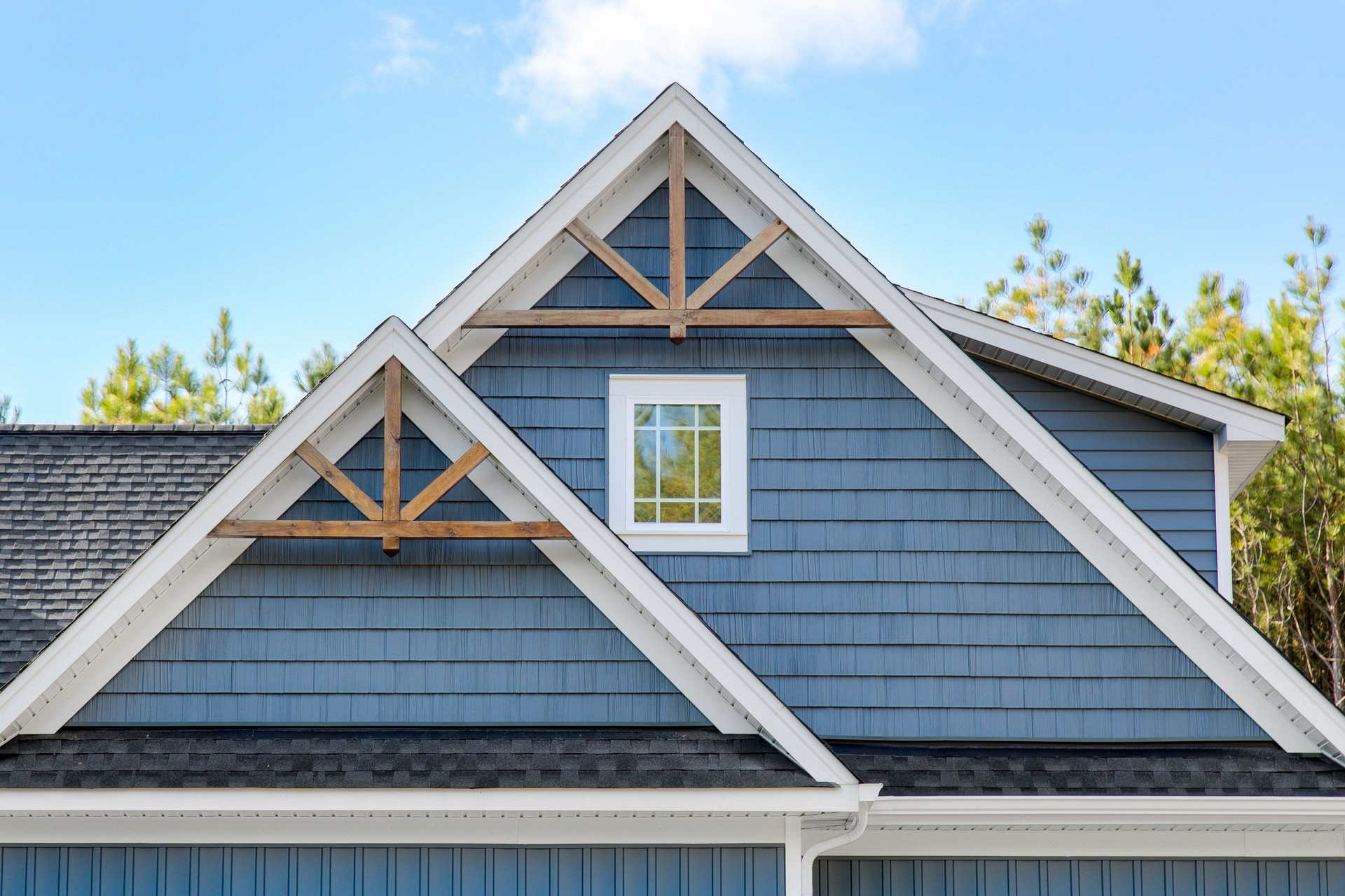 Blue House Gable Roof With Wooden Trusses And A Window Under A Clear Sky